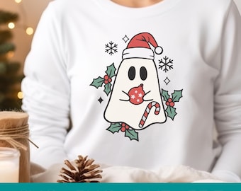 May include: White sweatshirt featuring a cartoon ghost wearing a Santa hat and holding a Christmas ornament and candy cane. The design includes snowflakes, holly, and the text "SVG / PNG / DXF / PDF" at the bottom.