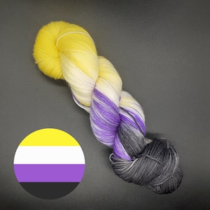 May include: A skein of yarn with yellow, white, purple and black stripes. The yarn is wound into a ball shape.