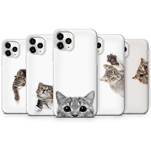 May include: Four white iPhone cases featuring different images of cats peeking out of holes. The cases are all clear and reveal the phone's camera lenses.