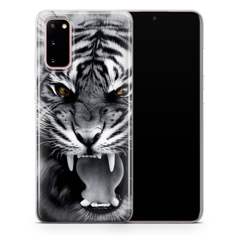 May include: A clear phone case with a black and white image of a tiger's face. The tiger is roaring with its mouth open and its teeth showing. The phone case is designed for a Samsung Galaxy S20.