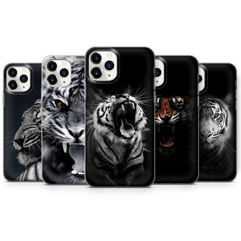 May include: Five different iPhone cases with tiger designs. The cases are black with a clear back and feature different tiger images, including a white tiger roaring, a white tiger with its mouth closed, a black and white tiger roaring, a brown and orange tiger roaring, and a white tiger with its mouth closed.
