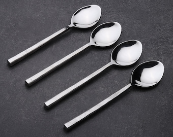 Puede incluir: Cuatro cucharas de plata con acabado pulido. Las cucharas están dispuestas en fila, con los mangos apuntando hacia la derecha.