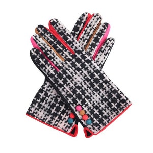 Könnte beinhalten: Ein Paar Handschuhe mit einem schwarz-weißen Hahnentrittmuster. Die Handschuhe haben rote, rosa und beige Akzente an den Fingern und eine rote Einfassung. Bunte Pompons schmücken den Handgelenkbereich.