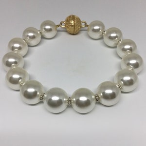 May include: A white pearl bracelet with a gold magnetic clasp.