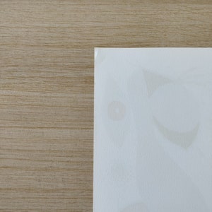 May include: A close-up of a white surface with faint, light brown stains. The surface is textured and has a subtle sheen.