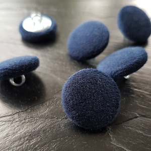 May include: Six dark blue round buttons with a silver shank. The buttons are made of a soft, fuzzy material.