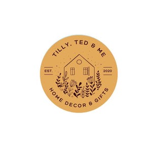 May include: A circular logo with a mustard yellow background featuring dark brown line art of a house surrounded by wildflowers. The text reads TILLY, TED & ME, EST. 2020, and HOME DECOR & GIFTS, arranged in a circular pattern around the central house.