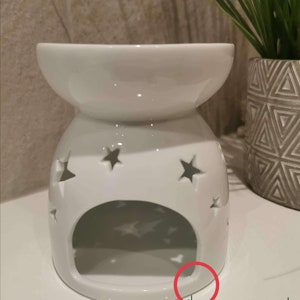 May include: White ceramic oil burner with a star design and a small slit on the front.