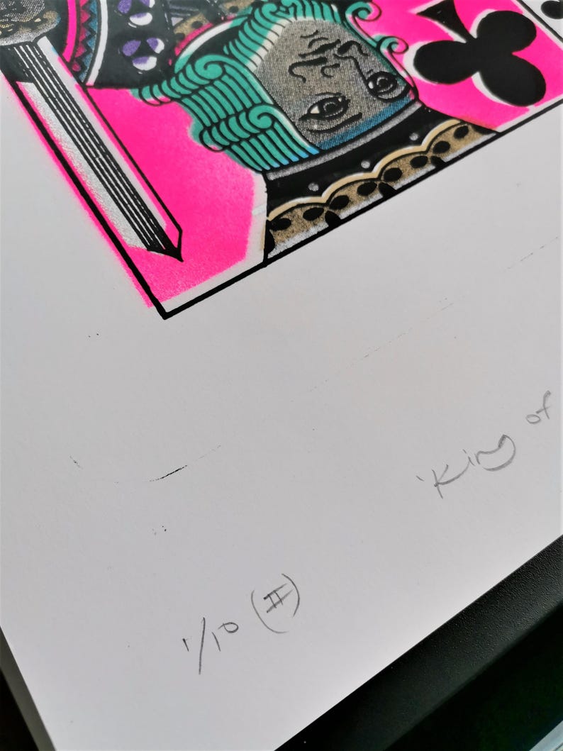 K&ouml;nnte beinhalten: Eine pinkfarbene und schwarze Spielkarte mit einer gr&uuml;nen und schwarzen Illustration des K&ouml;nigs der Kreuz. Die Karte ist mit 1/10 (#) nummeriert und hat den Text 'King of' in der unteren rechten Ecke.