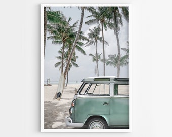 May include: A vintage green van parked on a sandy beach with palm trees in the background. A white surfboard leans against the van.