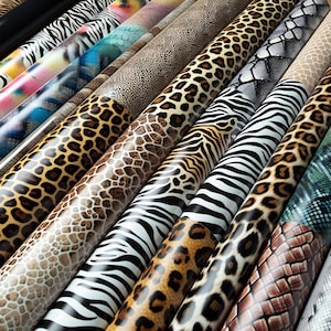 May include: A variety of patterned vinyl rolls, including zebra, leopard, snake, and giraffe prints. The rolls are arranged in a row, with the patterns facing the viewer.