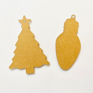 May include: Two brown wooden Christmas ornaments, one shaped like a Christmas tree and the other shaped like a light bulb.