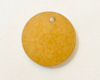 May include: A round, yellow wooden tag with a small hole in the center.