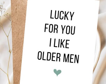 Puede incluir: Una tarjeta de felicitación blanca con el texto "LUCKY FOR YOU I LIKE OLDER MEN" en negro, con un corazón verde azulado en la parte inferior. La tarjeta está en un sobre marrón.