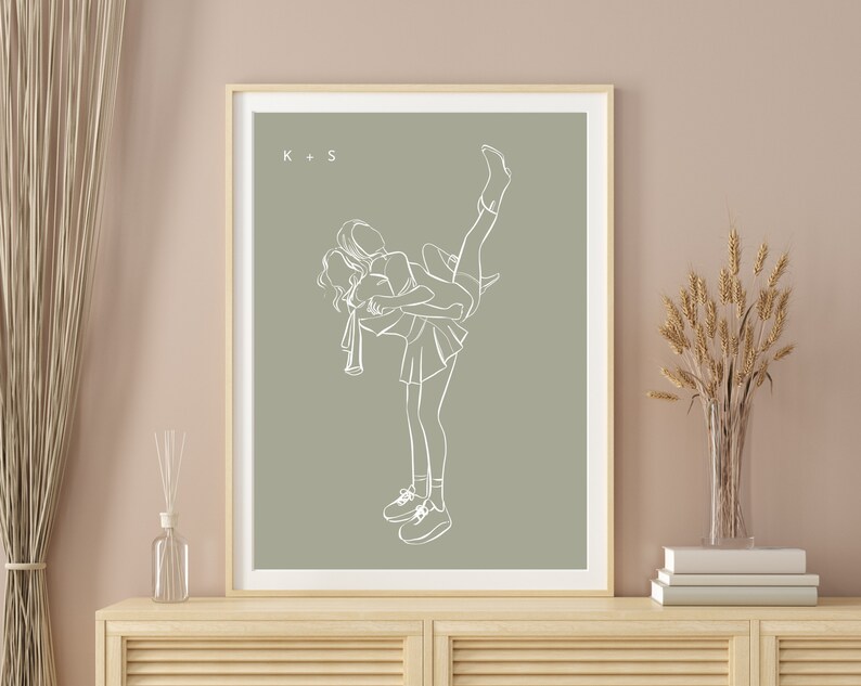 May include: A line drawing of two people in a playful pose, one holding the other in the air. The drawing is in white on a sage green background. The initials "K + S" are in the top left corner.