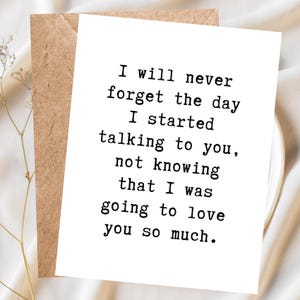 May include: A white rectangular greeting card with black typewriter-style text that reads: I will never forget the day I started talking to you, not knowing that I was going to love you so much. The card is placed against a brown envelope.