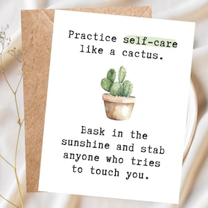 May include: A white greeting card with black text that reads Practice self-care like a cactus. Bask in the sunshine and stab anyone who tries to touch you. A watercolor illustration of a green cactus in a brown pot is centered on the card.