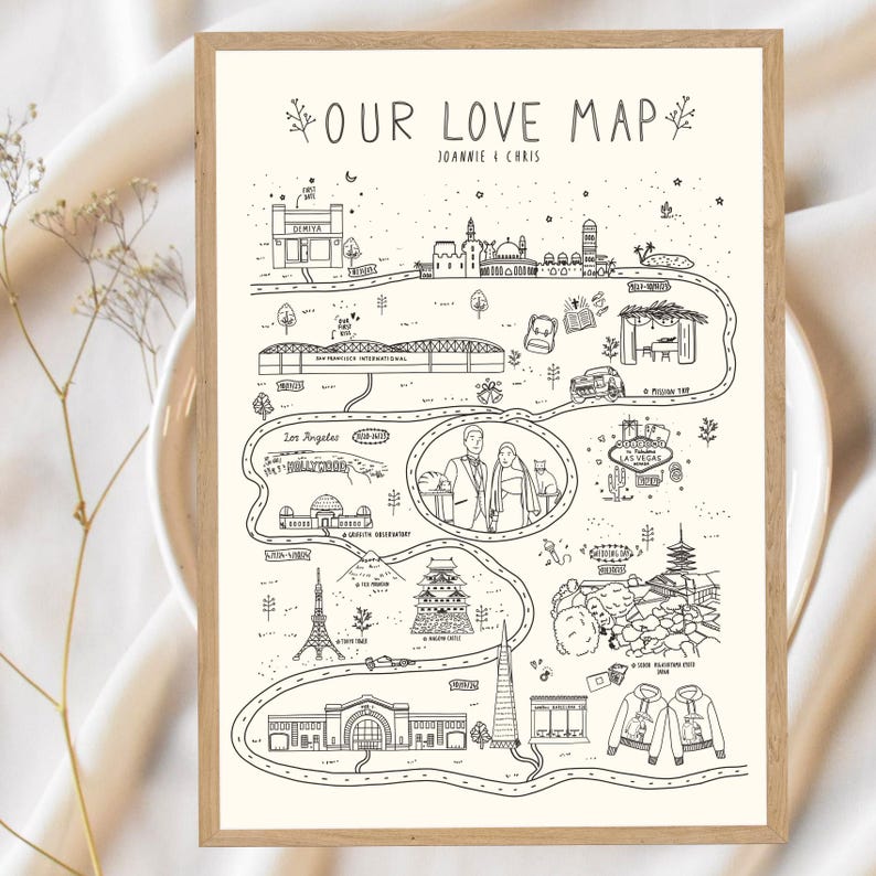 May include: A framed black and white illustrated map titled "OUR LOVE MAP" with the names "Joannie & Chris" at the top. The map depicts various locations with illustrations of landmarks and icons, including a train station, the Eiffel Tower, and the Las Vegas sign.