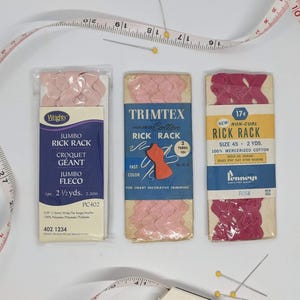 May include: Three packages of pink and red rickrack trim. The packages are labeled with the brand names Wrights, Trimtex, and Penneys. The packages contain 2 1/2 yards of trim.