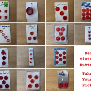 May include: Assortment of red vintage buttons in various shapes and sizes, including round, star, and flower designs. The buttons are displayed on small cards with labels like "Le Bouton", "La Moderne", and "Lansing".