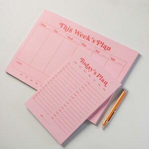 May include: Pink weekly and daily planner pads with a retro font. The weekly planner has space for each day of the week, Monday through Saturday. The daily planner has space for each hour of the day, from 7 am to 8 pm.