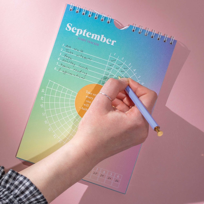 May include: A colourful habit tracker with a grid for tracking daily habits. The grid is labelled with numbers 1 through 6 and the days of the week. The habit tracker is open to September and has a quote that reads "Take small steps every day, one at a time, and you will succeed." - Author Unknown.
