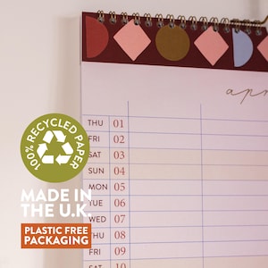 May include: A spiral-bound desk calendar with a burgundy header featuring geometric shapes in pink, brown, and blue. The calendar displays the month of April, with the text "100% Recycled Paper", "Made in the U.K.", and "Plastic Free Packaging".