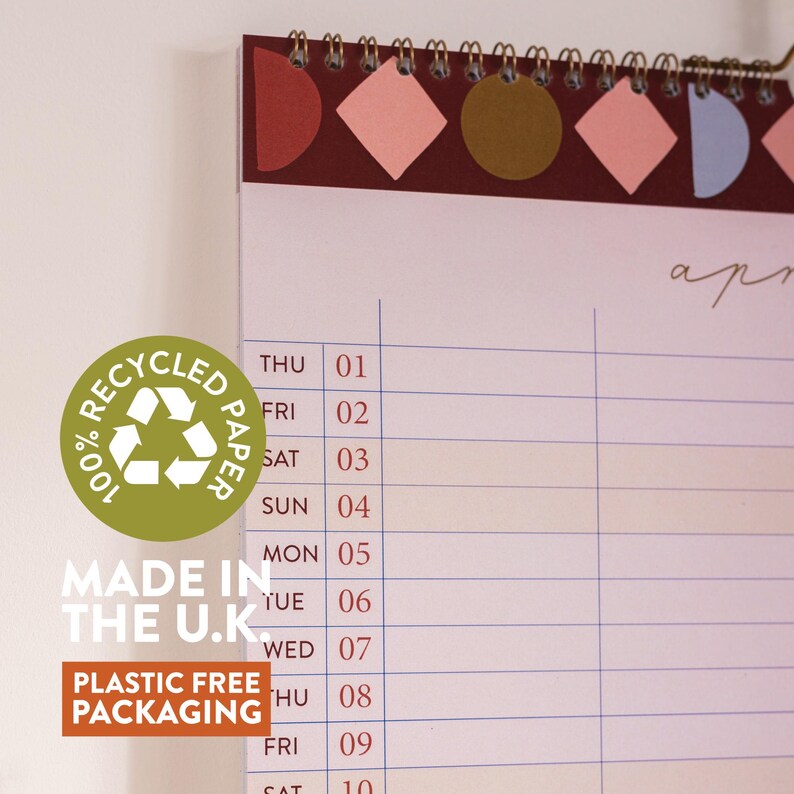 May include: A spiral-bound desk calendar with a burgundy header featuring geometric shapes in pink, brown, and blue. The calendar displays the month of April, with the text "100% Recycled Paper", "Made in the U.K.", and "Plastic Free Packaging".