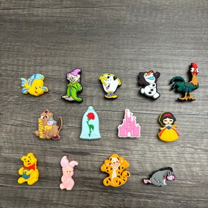 May include: A set of 14 colorful Disney character charms, including characters like Winnie the Pooh, Tigger, Snow White, and the Beast. The charms are made of a soft, flexible material and are perfect for adding a touch of Disney magic to your belongings.