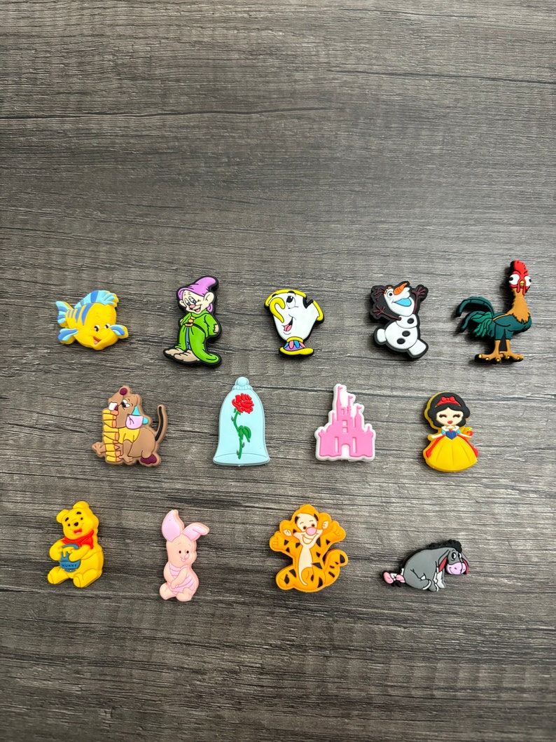 May include: A set of 14 colorful Disney character charms, including characters like Winnie the Pooh, Tigger, Snow White, and the Beast. The charms are made of a soft, flexible material and are perfect for adding a touch of Disney magic to your belongings.