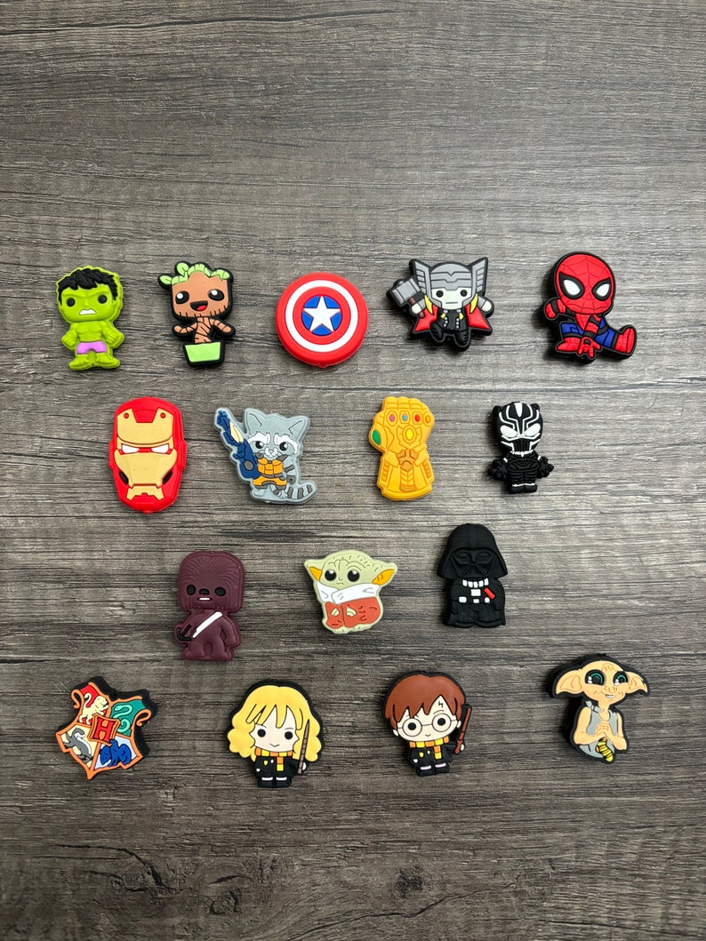 May include: A collection of 15 colorful cartoon character shoe charms featuring characters from popular movies and TV shows, including Marvel, Star Wars, and Harry Potter. The charms are made of rubber and have a variety of colors and designs.