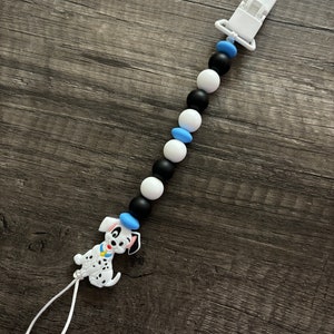 Peut inclure: Un attache-sucette en silicone blanc avec des perles noires et bleues et un charme de chien dalmatien.
