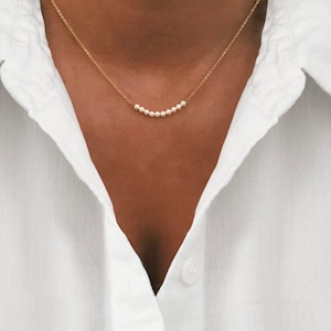 Peut inclure: Un collier délicat en chaîne dorée avec une rangée de petites perles blanches.