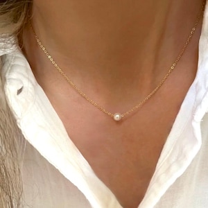 Puede incluir: Un delicado collar de cadena dorada con un solo colgante de perla blanca.