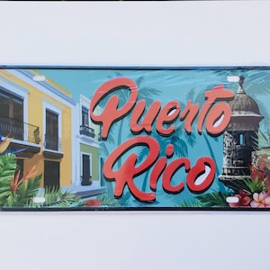 May include: A colorful metal sign with a blue background and the words "Puerto Rico" in red. The sign features a depiction of a building with a balcony and a palm tree.
