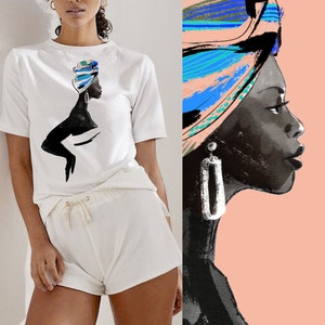 May include: A white t-shirt featuring a black silhouette of a woman wearing a colourful head wrap. The woman is looking to the right. The t-shirt is paired with white shorts.