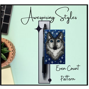 May include: A beaded wolf head pattern on a blue background with white snowflakes. The pattern is an even count pattern. The beadwork is displayed on a pen.