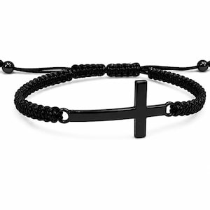May include: A black bracelet featuring a central horizontal cross charm made of polished black metal. The band is constructed from braided black cord with an adjustable sliding knot closure and small black beads at the ends of the pull strings.