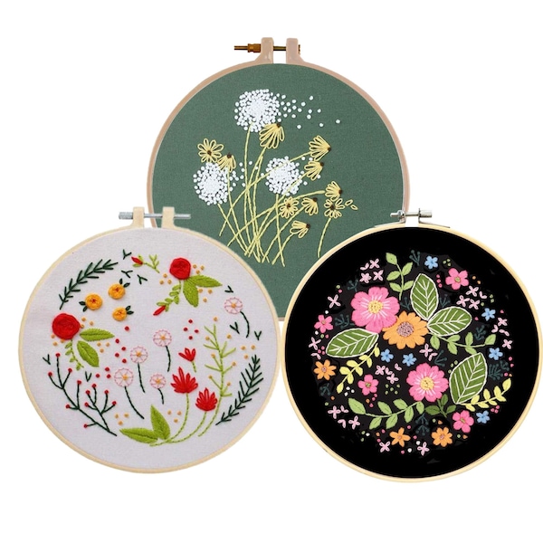 Puede incluir: Tres aros de bordado con diseños florales. Uno presenta dientes de león blancos sobre un fondo verde. Otro tiene flores rojas y amarillas sobre un fondo blanco. El tercero tiene flores rosas y naranjas sobre un fondo negro.