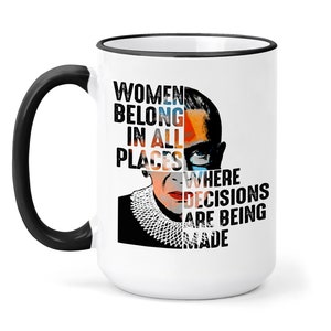May include: White ceramic mug with a black handle and black rim. The mug features a colorful portrait of Ruth Bader Ginsburg and the text "Women belong in all places where decisions are being made."
