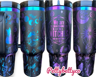 Puede incluir: Un vaso de acero inoxidable negro con un acabado iridiscente morado y azul. El vaso presenta un diseño de lunas, estrellas, cristales, un gato, hongos y el texto "We are the granddaughters of the witches you couldn't burn".