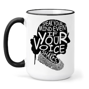 May include: White ceramic mug with a black rim and handle. The mug features a black silhouette of a woman with the text "Speak your mind even if your voice shakes."