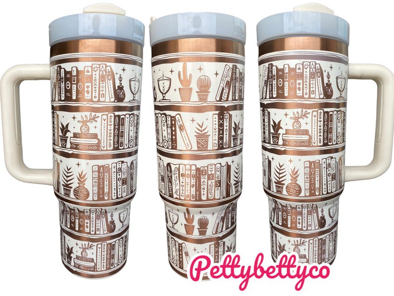 May include: A white and copper travel mug with a white lid and handle. The mug features a design of books on shelves with a copper finish. The text "Pettybettyco" is printed on the bottom of the mug.