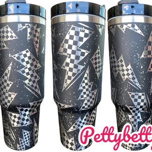 May include: Three stainless steel tumblers with a black and silver checkered lightning bolt pattern. The tumblers have a black lid and a handle.