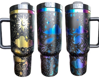May include: Three stainless steel travel mugs with a black background and a galaxy print. The mugs have a handle and a lid. The galaxy print features stars, planets, and clouds in gold, blue, and purple.