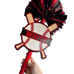 May include: A red and black baseball-themed spirit stick with a white baseball design and the word "WHITE" in red letters. The stick has a red handle and a black and red pom-pom. The baseball design includes crossed bats.