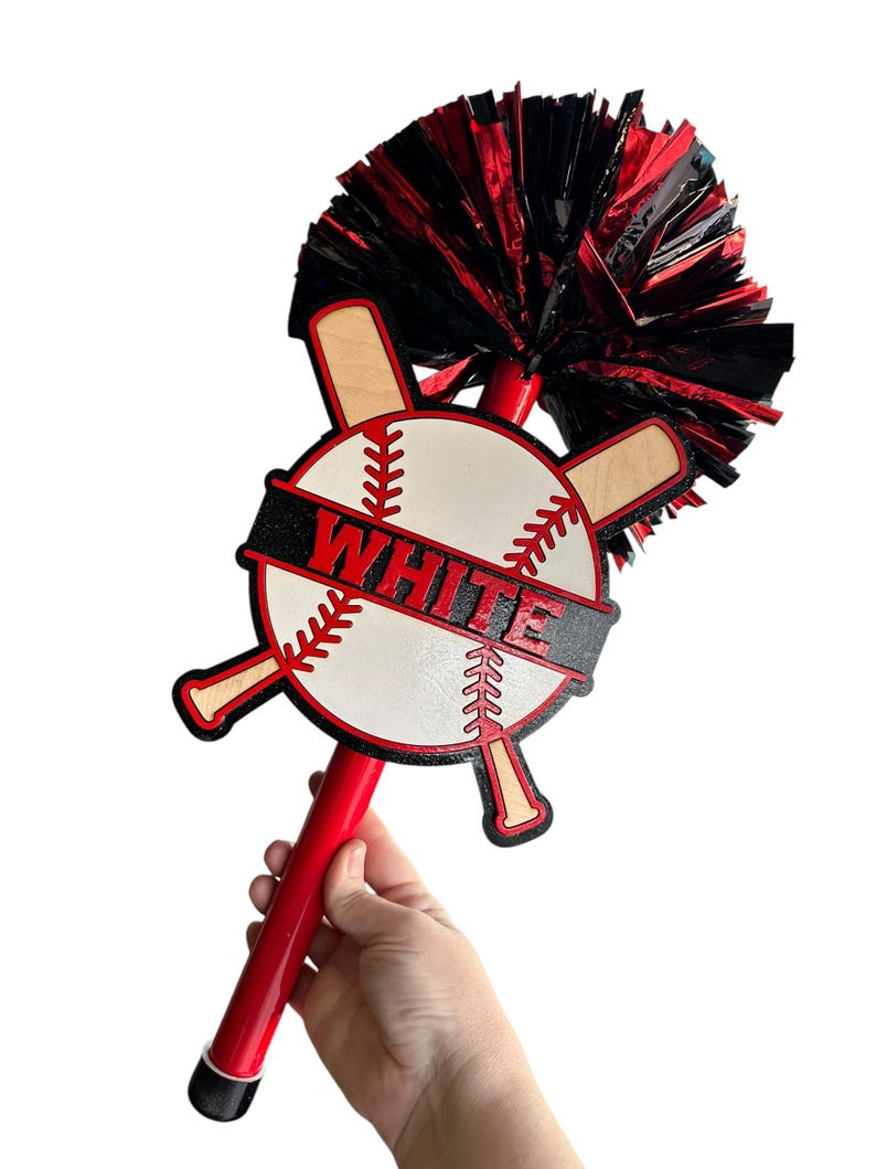 May include: A red and black baseball-themed spirit stick with a white baseball design and the word "WHITE" in red letters. The stick has a red handle and a black and red pom-pom. The baseball design includes crossed bats.