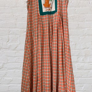 May include: A sleeveless, orange and green plaid dress with a square patch featuring a cartoon tiger on the front.