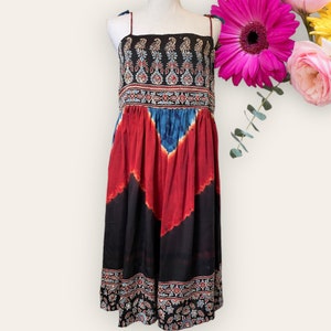 May include: A black, red, and blue tie-dye maxi dress with a paisley print around the neckline and hem. The dress has thin straps and a gathered waist.