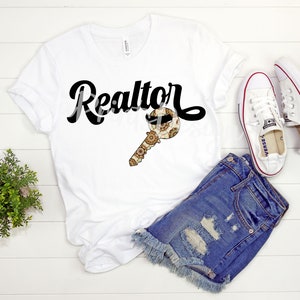 May include: White t-shirt with black text that says "Realtor" and a gold key with a patterned design. The key has a moustache and sunglasses on it.